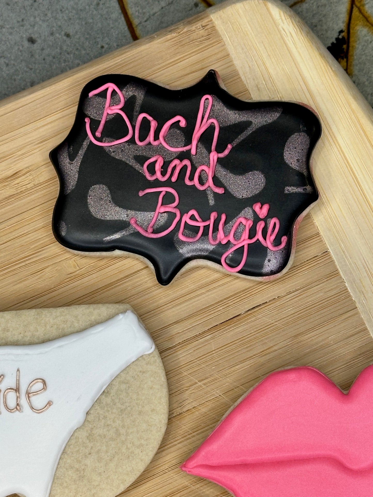 custom bachelorette sugar cookies- black sugar cookie with bach and bougie writing and rose gold heels
