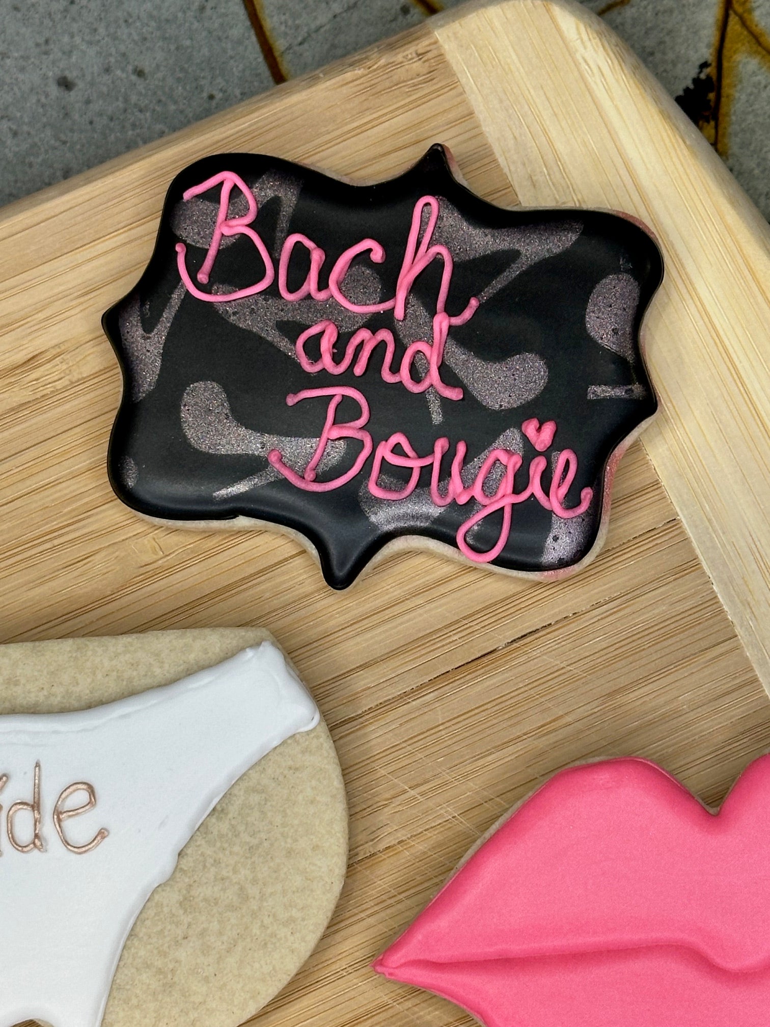custom bachelorette sugar cookies- black sugar cookie with bach and bougie writing and rose gold heels